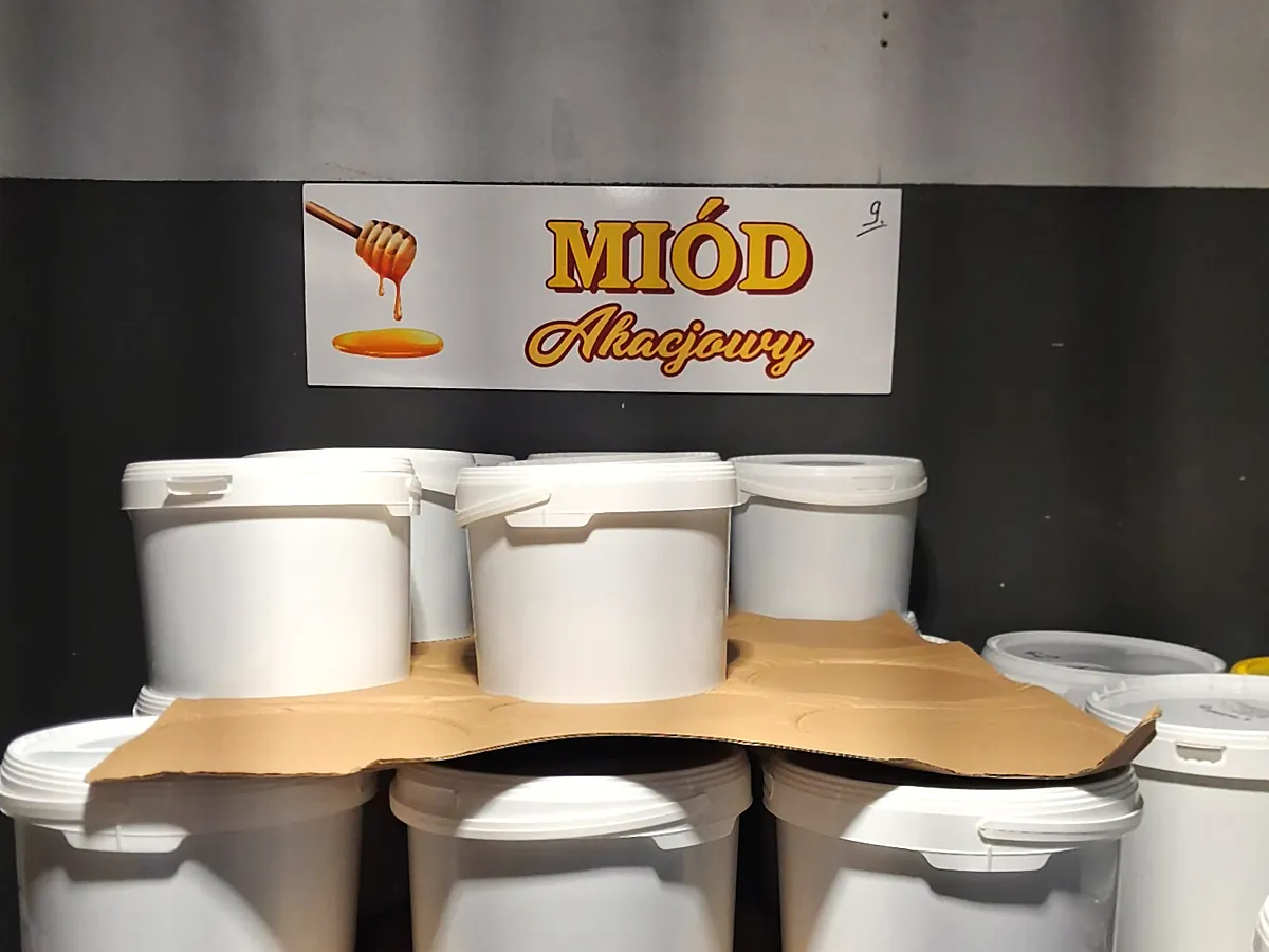 Wiadra miodu akacjowego na paletach